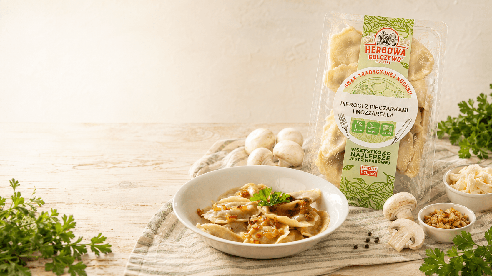 Pierogi z pieczarką i mozzarellą Herbowa na talerzu, z opakowaniem i składnikami na jasnym stole.