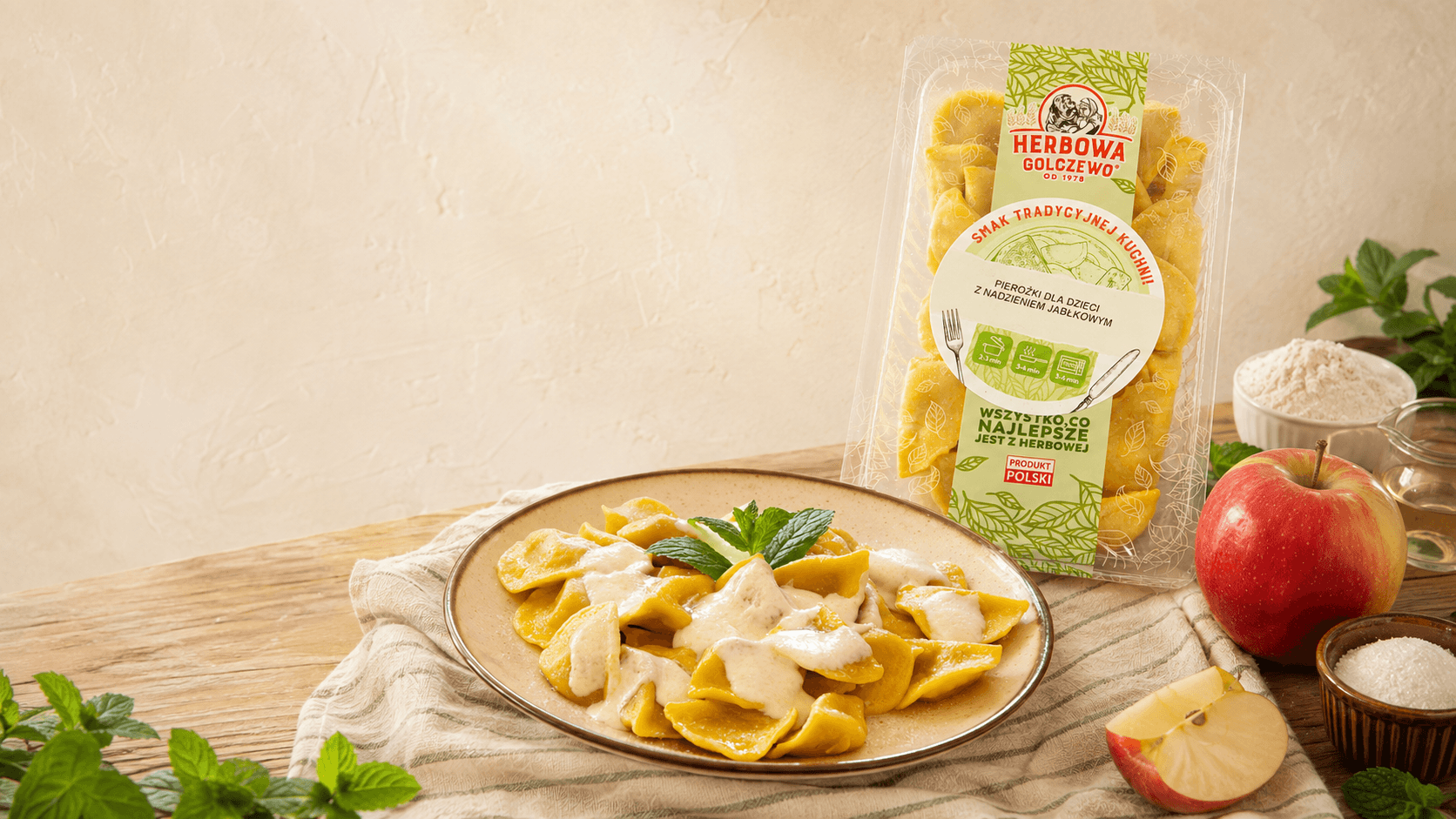 Pierożki z nadzieniem jabłkowym Herbowa na talerzu, z opakowaniem i składnikami na jasnym stole.