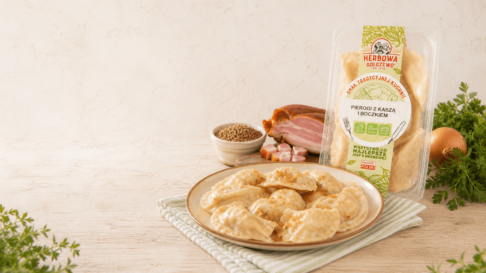 Pierogi z kaszą i boczkiem Herbowa na talerzu, z opakowaniem i składnikami na jasnym stole.