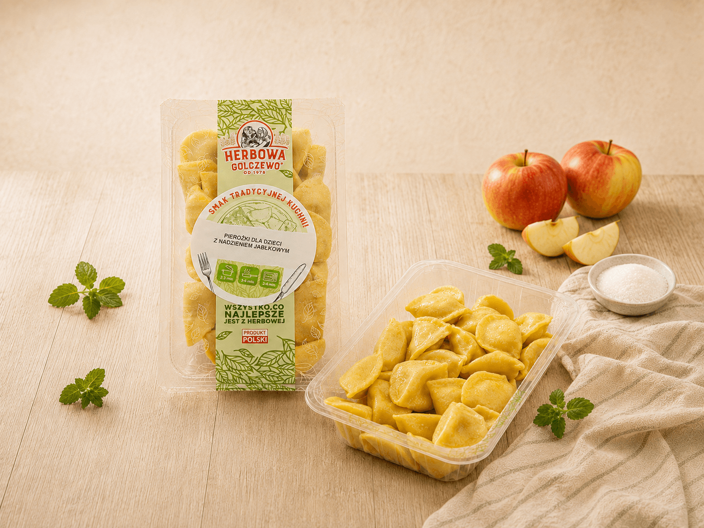 Pierożki z nadzieniem jabłkowym Herbowa — zestawienie zamkniętego i otwartego przezroczystego opakowania z dodatkami zgodnymi ze składem.